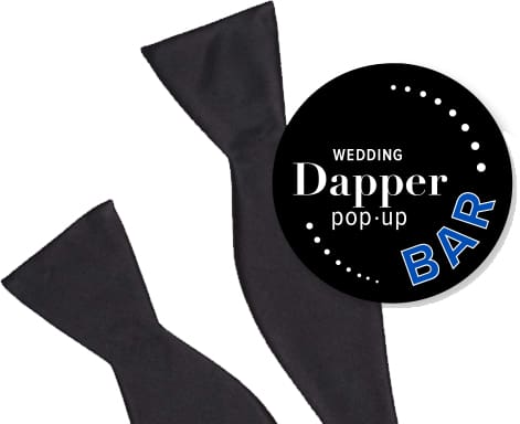 Black bow tie with a circular label reading 'Dapper pop-up BAR' for weddings.